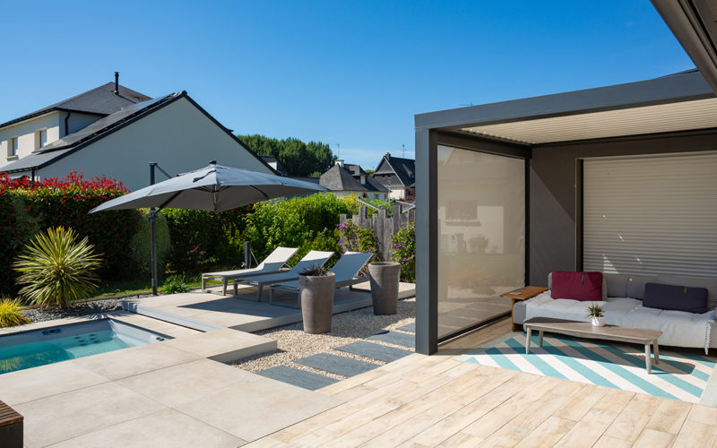 une piscine avec un salon de jardin et un pool house